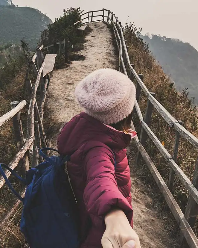 Viajera guiando de la mano por un sendero de montaña